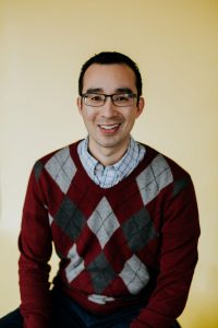 Headshot of smiling man in sweater